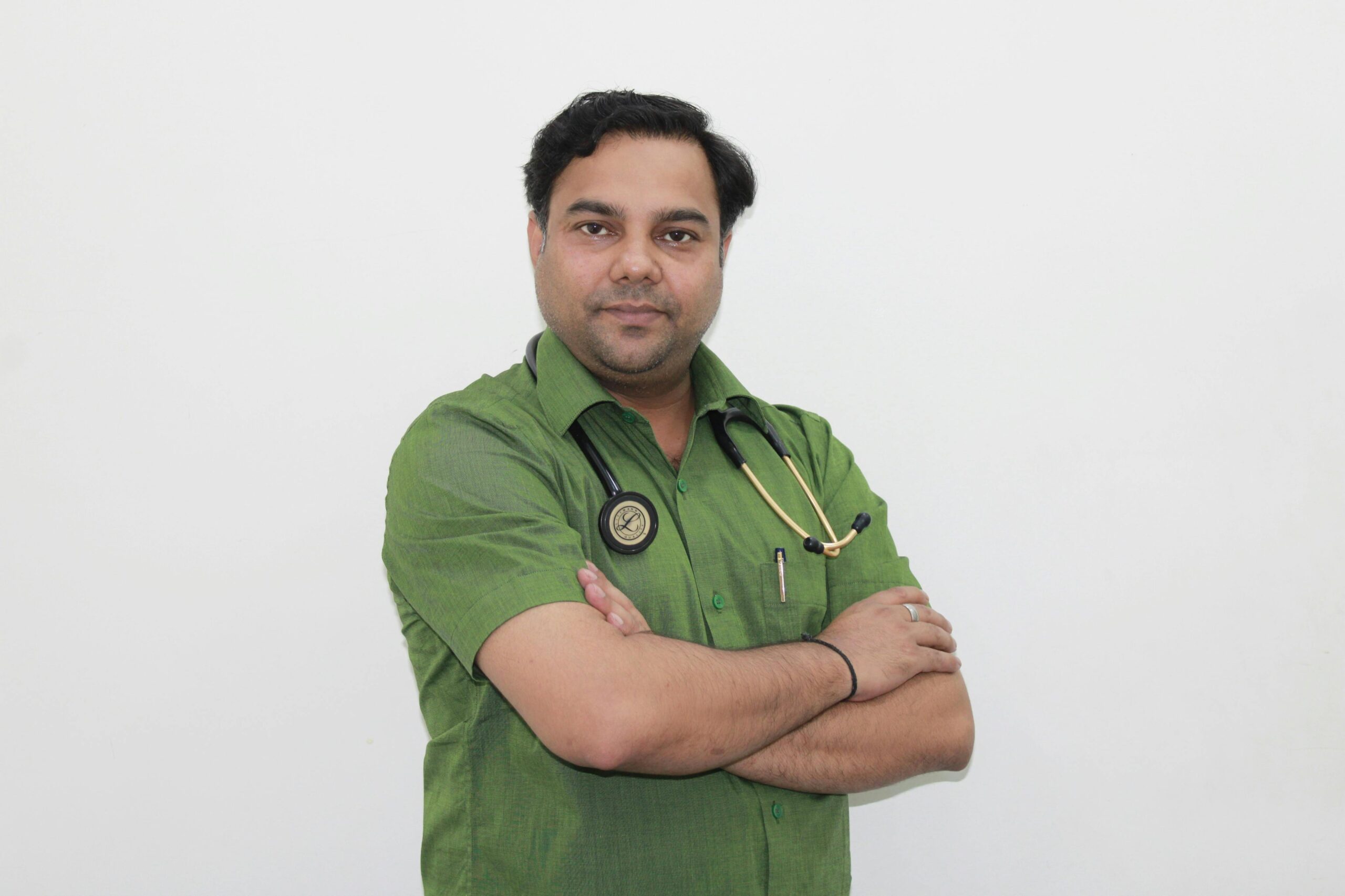 Portrait of a confident male doctor with stethoscope in a green shirt against a white background.