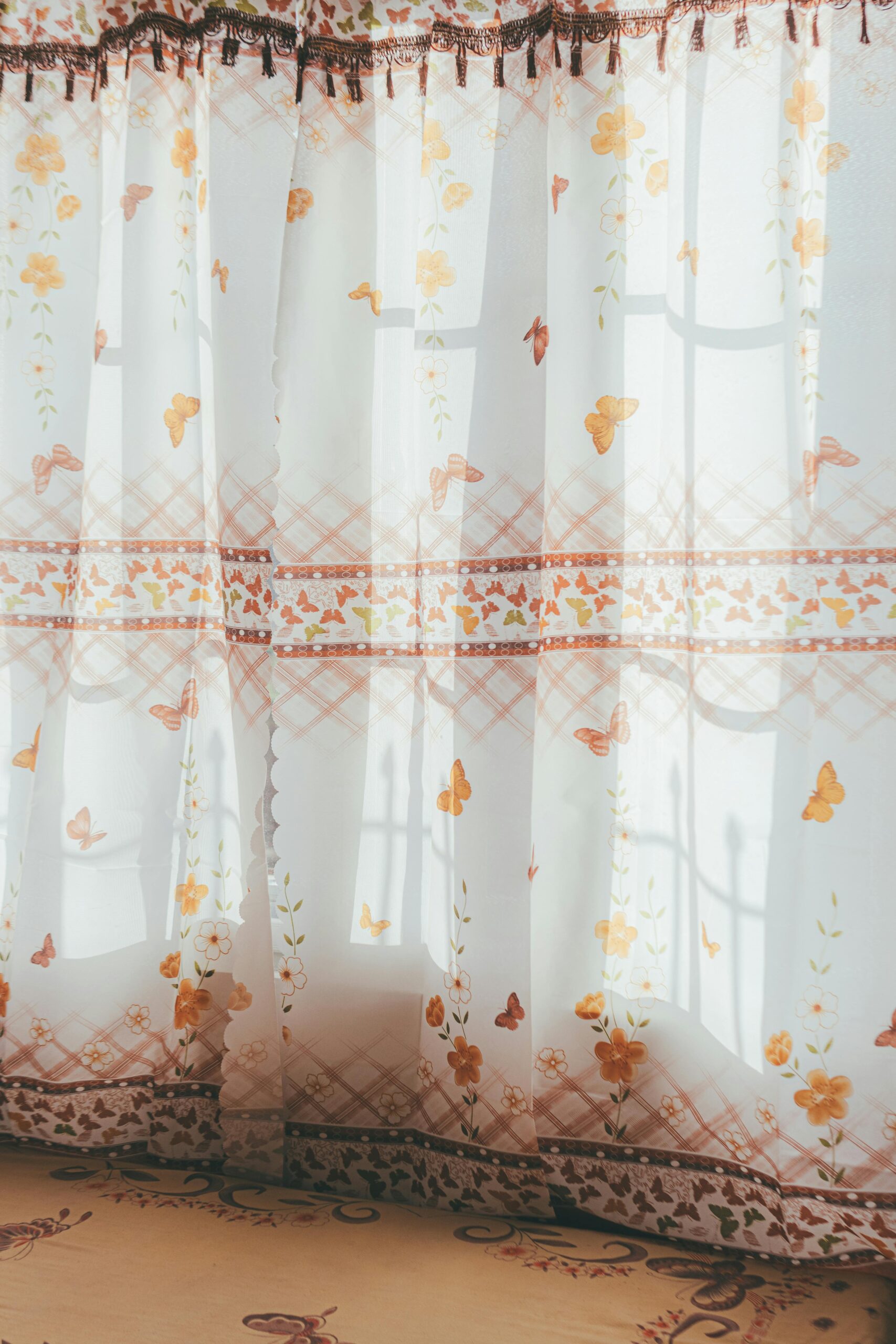Soft sunlight streaming through sheer curtains with floral patterns and butterfly designs.